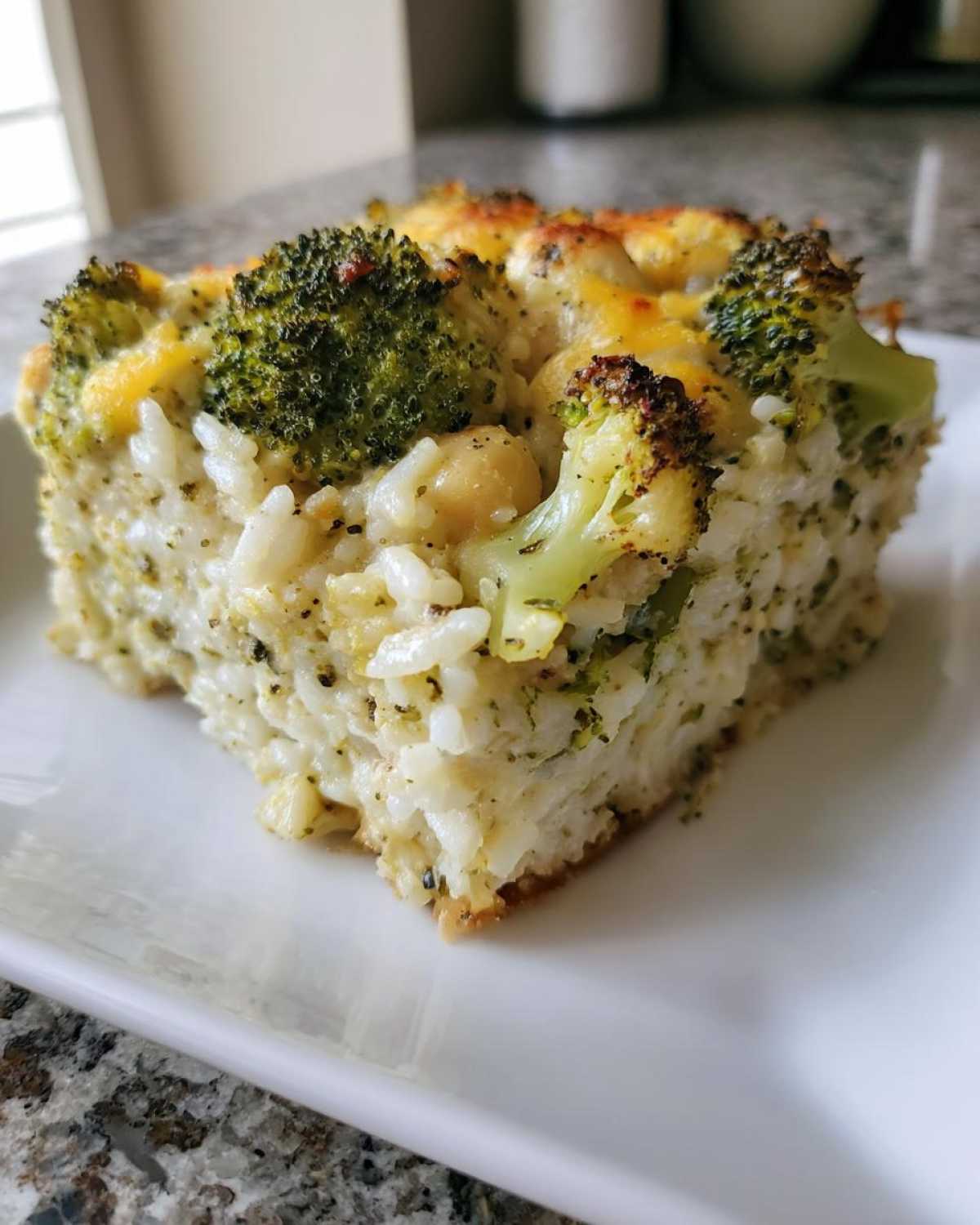 A square serving of baked Chickpea Broccoli Rice Casserole vegan meal, showing rice, broccoli florets, and chickpeas.