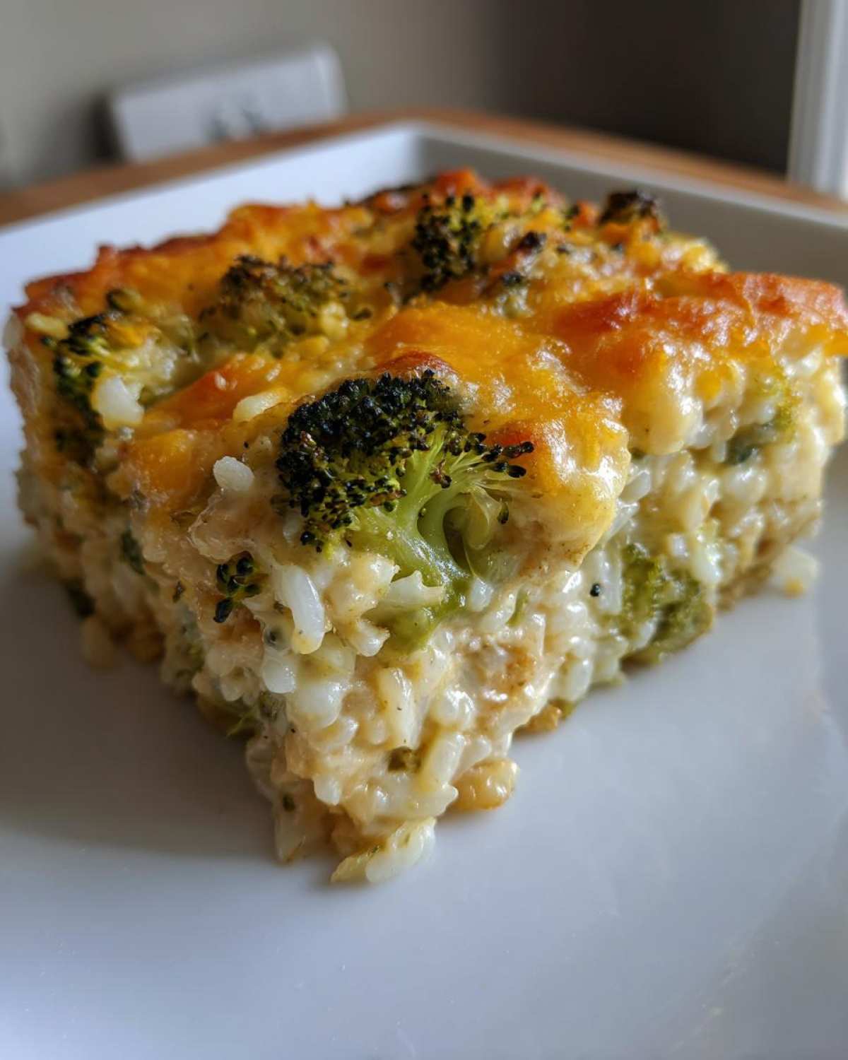 A close-up of a square serving of creamy Chickpea Broccoli Rice Casserole Vegan Meal with a golden-brown, cheesy top.