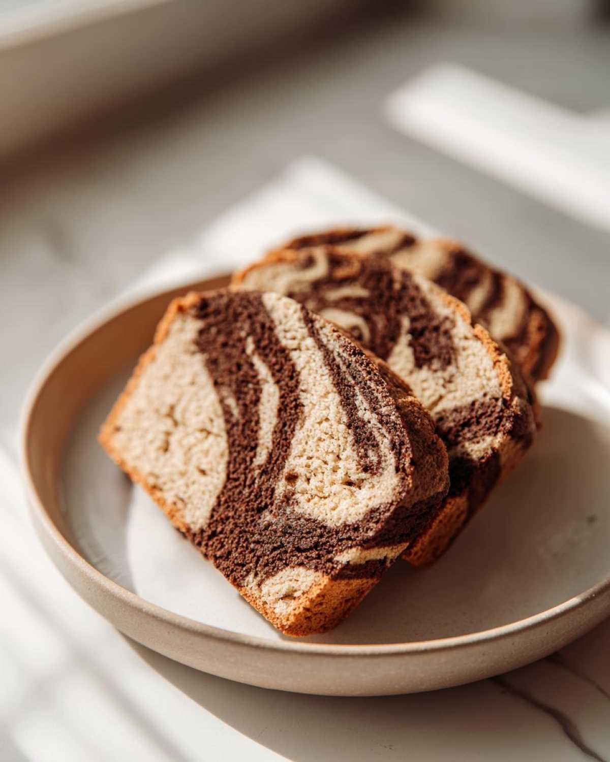 Three slices of rich Coffee Marble Cookies showing a distinct brown and tan swirl pattern, served on a light plate.