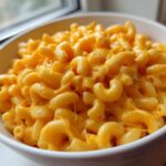 Close-up of a white bowl filled with rich, creamy, and cheesy Mac and Cheese.