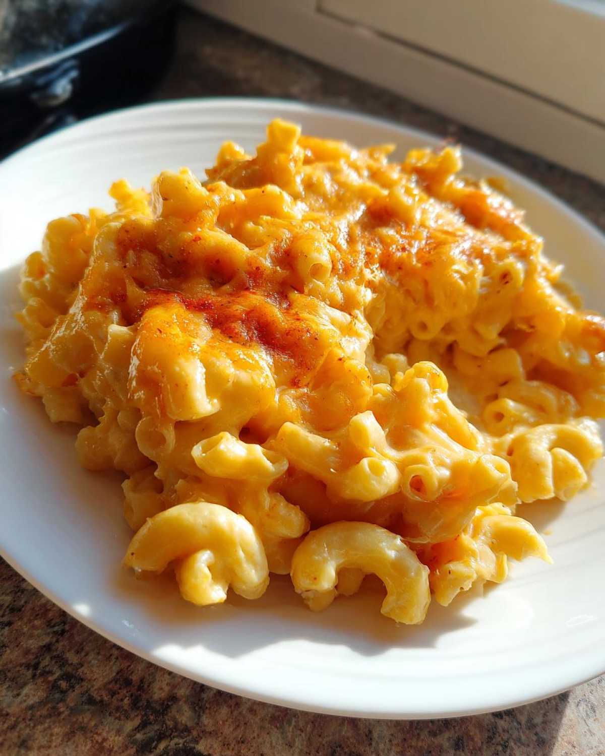 A close-up of creamy, cheesy Chick-fil-A Mac and Cheese served on a white plate, topped with melted cheese.