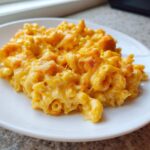 A close-up of creamy, cheesy Chick-fil-A Mac and Cheese with a slightly baked top, served on a white plate.