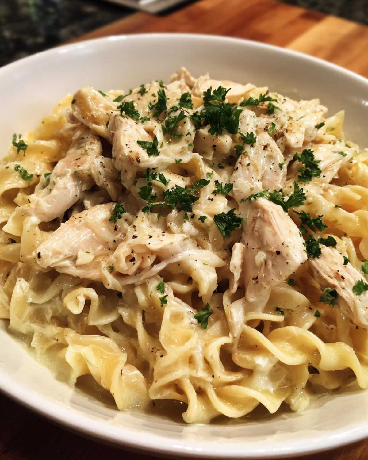 Close-up of creamy One Pot Chicken and Noodles topped with shredded chicken and fresh parsley.