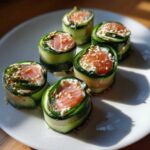 Five servings of low-carb Cucumber Sushi rolls filled with salmon and cream cheese, topped with sesame seeds.