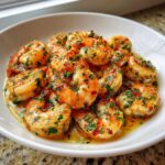 A white bowl filled with juicy Garlic Butter Sauteed Shrimp coated in a rich, buttery sauce with parsley and red pepper flakes.