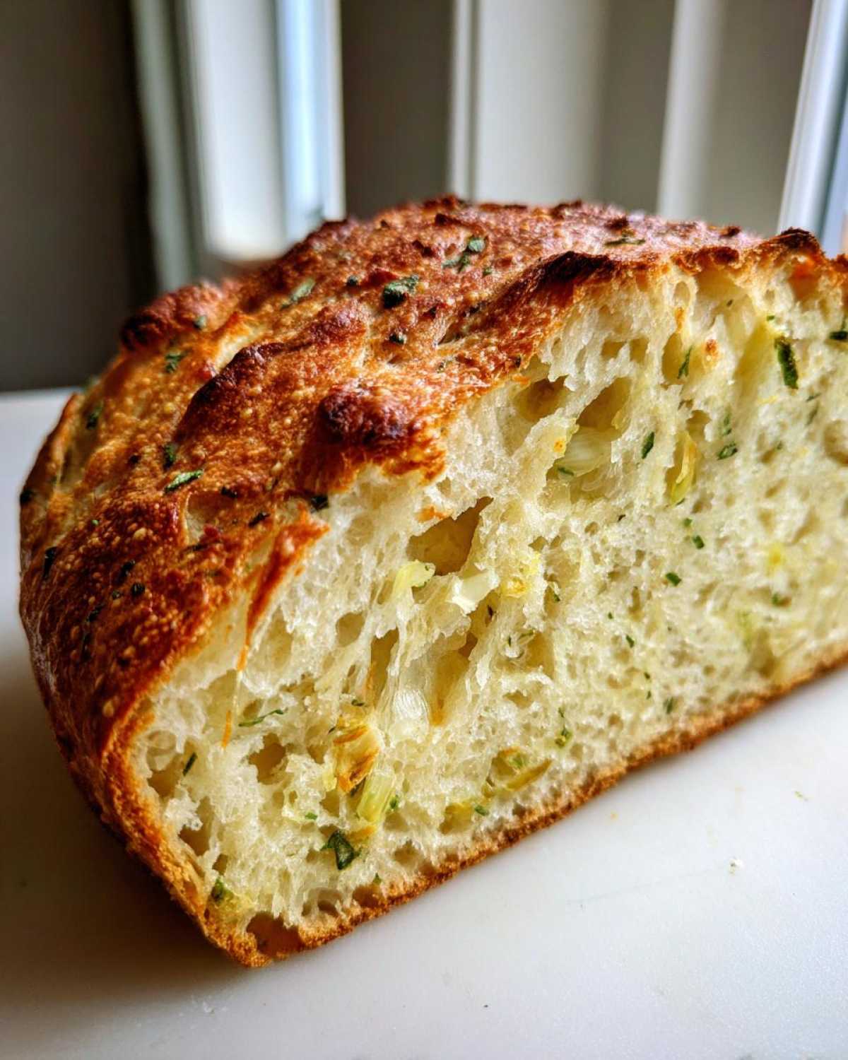 Close-up cross-section showing the airy, open crumb structure of the Garlic Herb Dutch Oven Bread with visible herbs.