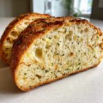 Close-up of the airy, soft interior (crumb) of Garlic Herb Dutch Oven Bread, studded with garlic and green herbs.