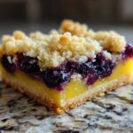 A single, thick slice of Lemon Blueberry Streusel Bars showing the shortbread crust, bright yellow lemon layer, blueberries, and crumb topping.