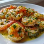 A close-up of succulent Lemon Garlic Shrimp coated in butter sauce and fresh parsley, served on a white plate.