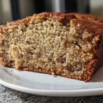 Close-up of a moist slice of banana bread showing the crumb texture and visible walnuts, ready to bake banana bread.