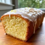 Close-up of a moist slice of homemade Lemon Bread topped with white glaze and lemon zest.