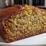 Close-up of a thick slice of moist Banana Bread showing its golden brown crust and tender crumb.