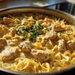Close-up of creamy One Pot Chicken and Noodles with egg noodles and chunks of chicken, garnished with parsley.