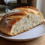 A cross-section of Quick and French Bread showing an open crumb and golden, scored crust on a white plate.
