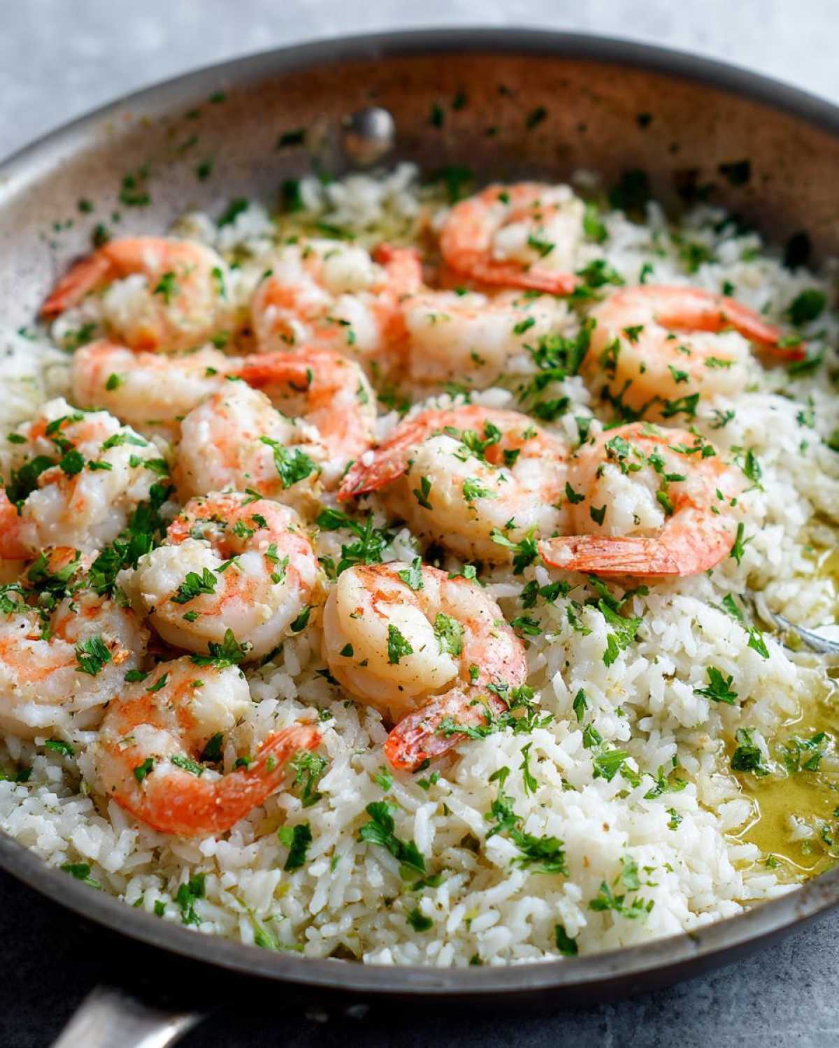 Close-up of Quick One-Pan Garlic Shrimp and Rice Recipe cooked in a stainless steel skillet, topped with parsley.