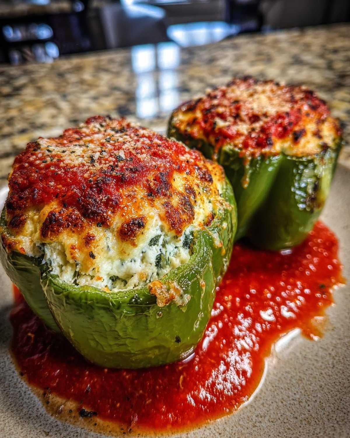 Two baked green bell peppers filled with creamy ricotta stuffing, topped with marinara and melted cheese, served in sauce.