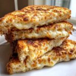 A stack of four golden-brown slices of Sliced Garlic Bread with Cheese showing gooey, melted cheese oozing out.