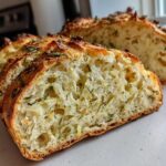 Close-up of sliced Garlic Herb Dutch Oven Bread showing a soft, open crumb filled with herbs and garlic.