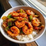 Close-up of a white bowl filled with white rice topped with seasoned Spicy Cajun Shrimp & Rice Bowl ingredients.
