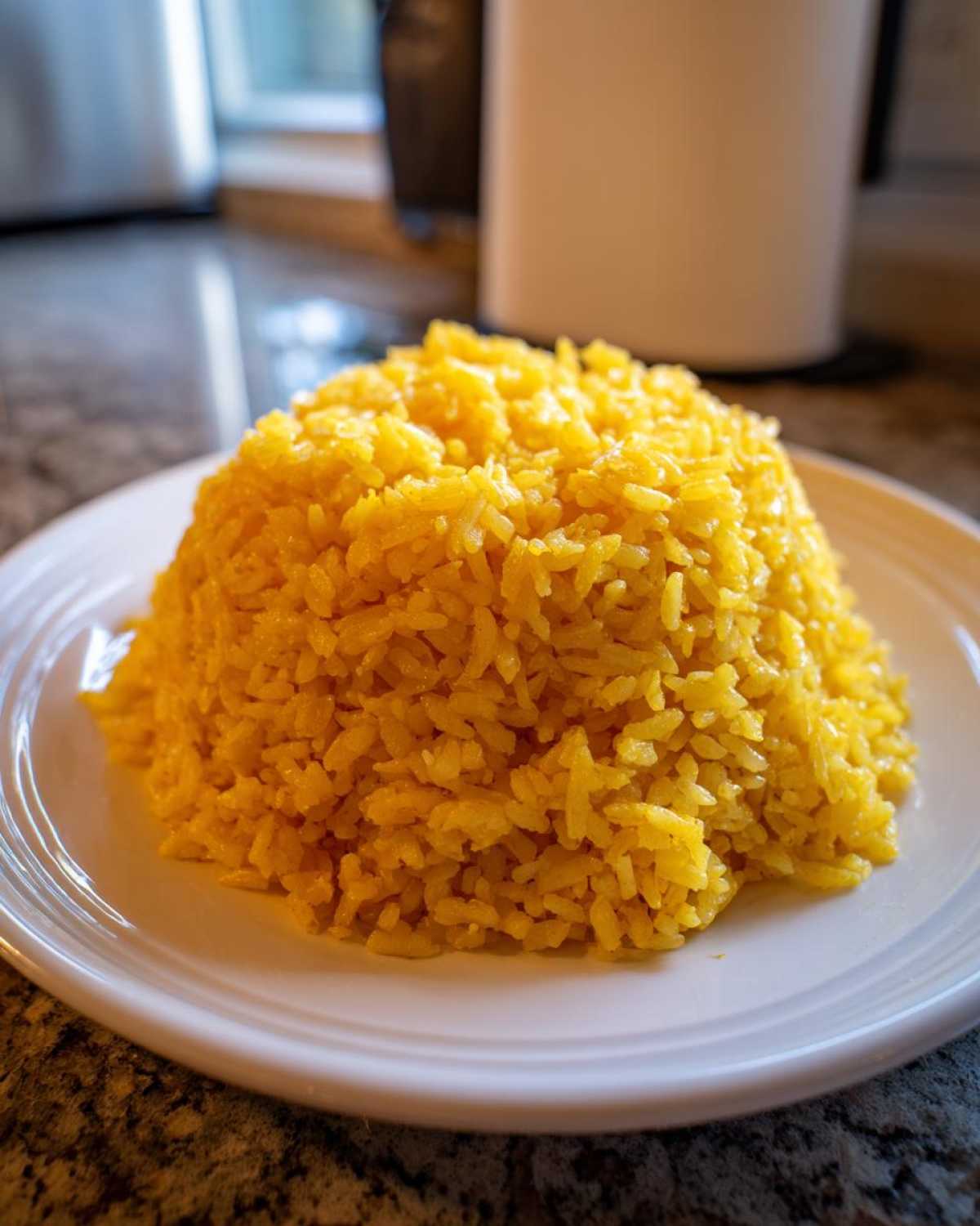 A perfectly molded mound of bright yellow Texas Roadhouse Seasoned Rice served on a white plate.