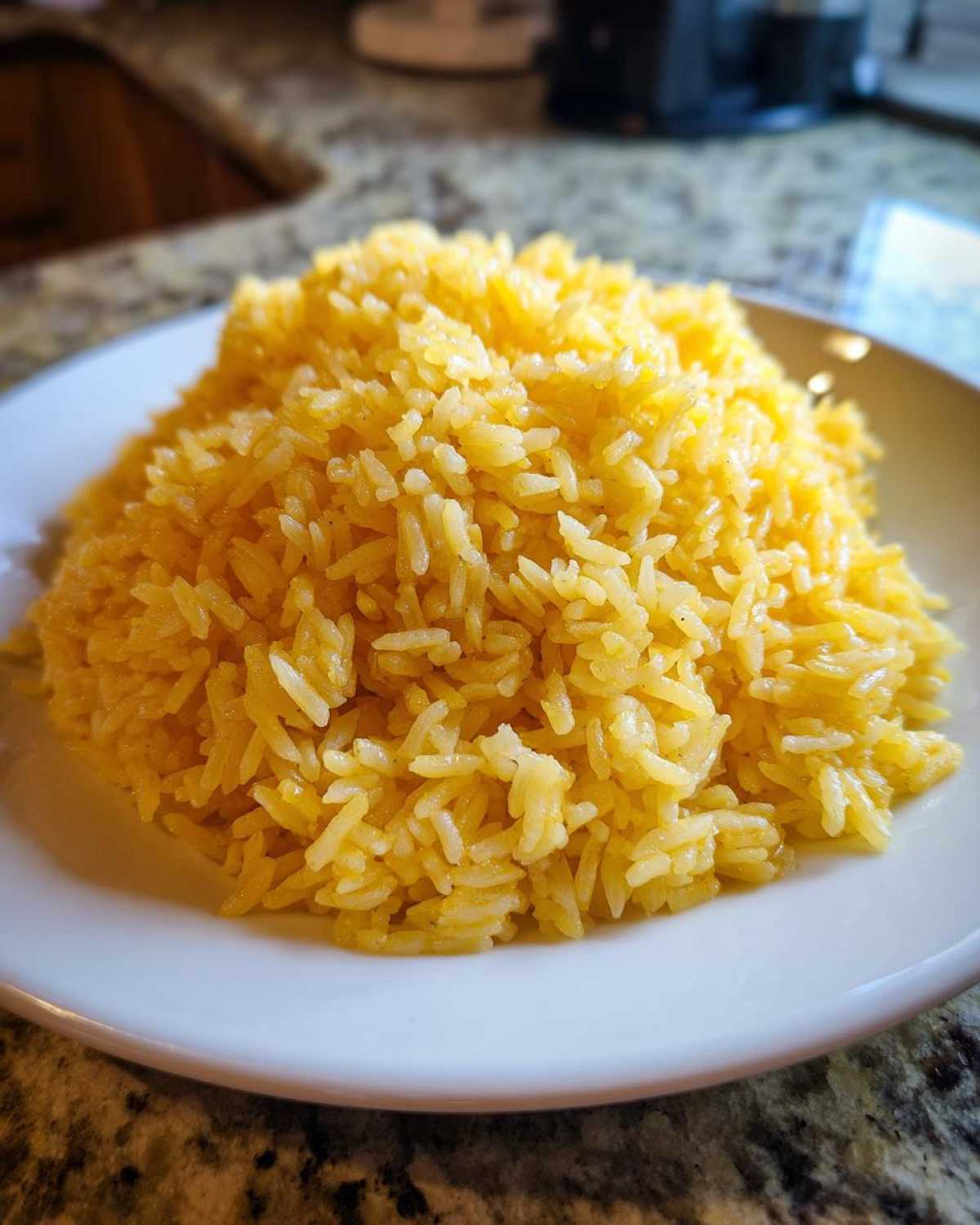 A close-up of a mound of bright yellow, fluffy Texas Roadhouse Seasoned Rice served on a white plate.